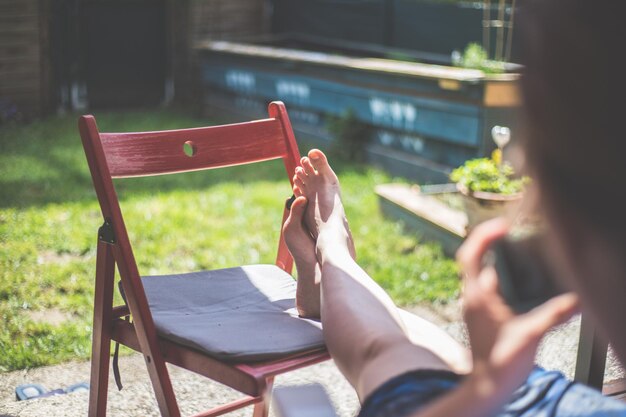 Fauler Tag zu Hause Sitzendes Mädchen genießt den Tag auf der Veranda mit ihrem Smartphone