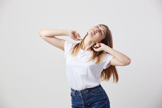 Faules Mädchen in einem weißen T-Shirt und Jeans ist auf weißem Hintergrund im Studio.