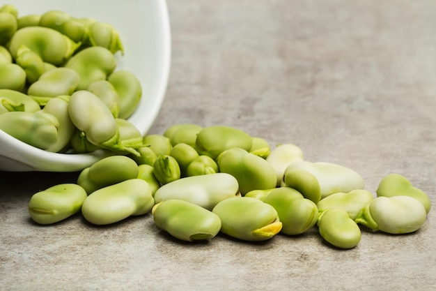 Favas em uma tigela branca e em uma bancada de cozinha de mármore