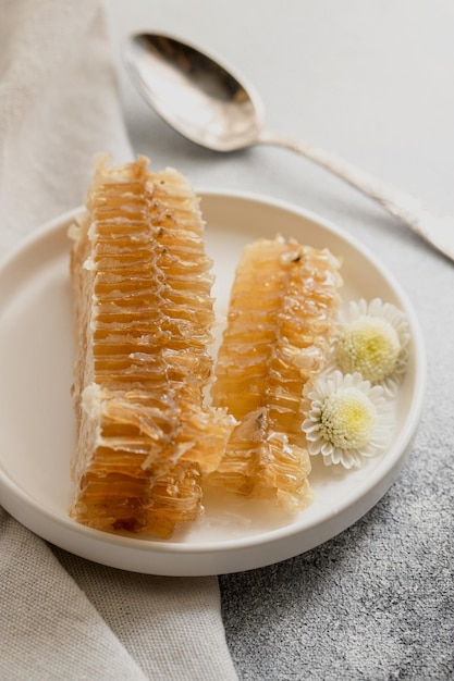 Favo de mel selado com colher em um prato de porcelana branca em uma mesa cinza