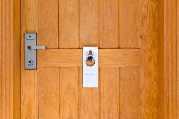 Foto por favor, no molestar la señal en la puerta de madera cerrada de la habitación del hotel