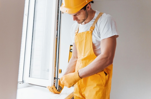 Faz-tudo de uniforme amarelo instala nova janela Concepção de renovação da casa