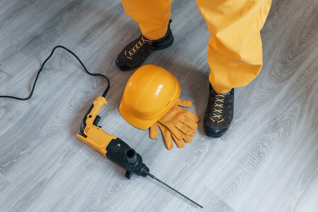 Faz-tudo em uniforme amarelo com broca em pé dentro de casa Concepção de renovação de casa