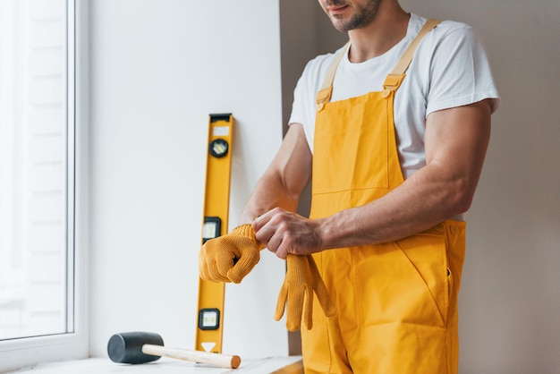 Faz-tudo em uniforme amarelo, preparando-se para o trabalho dentro de casa Concepção de renovação da casa