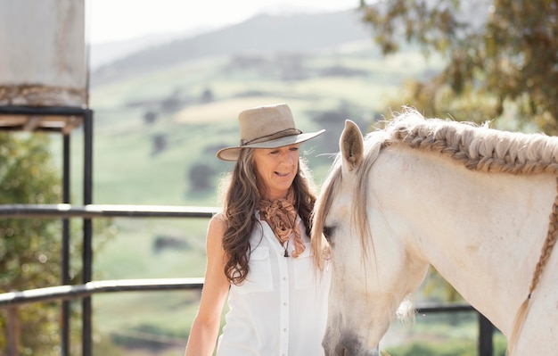 Fazendeira sorridente com seu cavalo no rancho