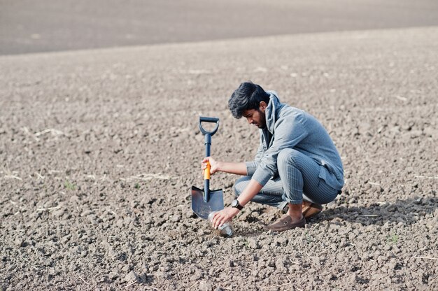 Fazendeiro asiático sul do engenheiro agrônomo com a pá que inspeciona o solo preto. Conceito de produção agrícola.