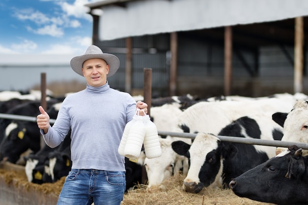 Fazendeiro com leite no fundo da fazenda de vacas