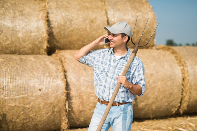 Fazendeiro de sorriso que fala no telefone quando no campo