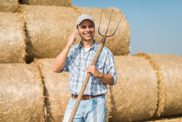 Fazendeiro de sorriso que fala no telefone quando no campo