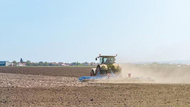 Fazendeiro em trator preparando o cultivador de canteiro. Paisagem do trator de agricultura.