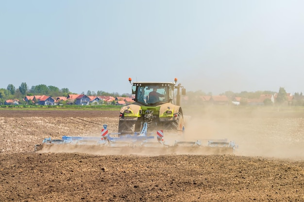 Fazendeiro em trator preparando o cultivador de canteiro. Paisagem do trator de agricultura.