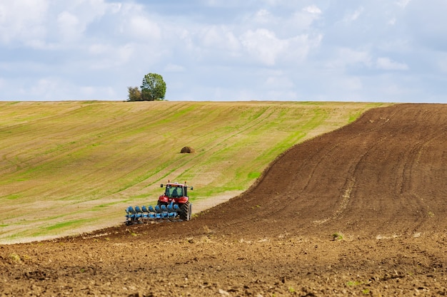 Fazendeiro em um trator ara a terra antes de semear com um cultivador de canteiro