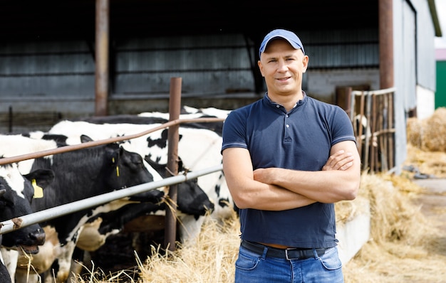 Fazendeiro positivo com vacas na fazenda