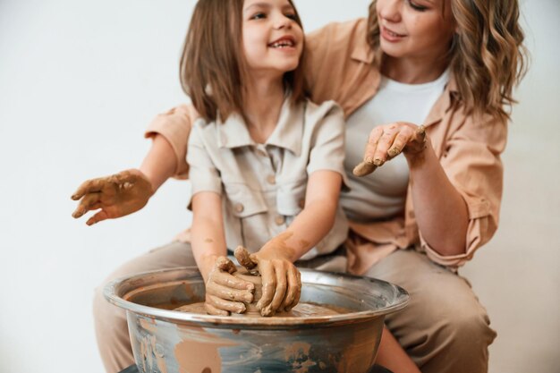 Foto fazendo a panela de barro mãe com a menina fazendo cerâmica em casa