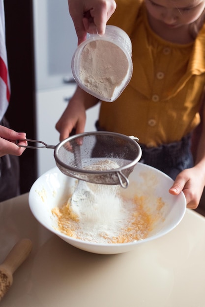 Fazendo biscoitos em casa, duas meninas cozinhando juntas colocam farinha na tigela