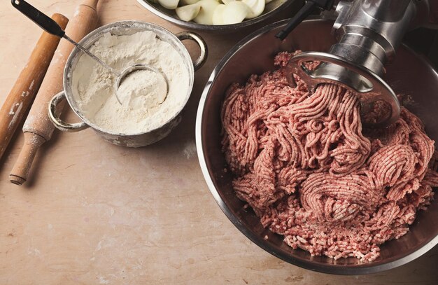 Fazendo bolinhos russos tradicionais. Farinha para massa e carne picada para rechear na mesa da cozinha, cozinhar ingredientes, copiar espaço