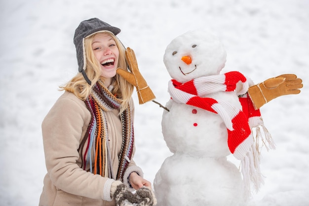 Fazendo boneco de neve e inverno divertido para as pessoas Retrato de inverno de uma jovem linda na neve Garden Win