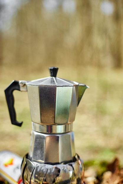 Fazendo café de acampamento de uma cafeteira gêiser em um queimador a gás