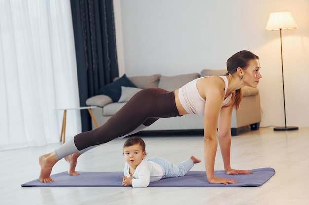 Fazendo exercícios no tapete mãe com sua filha está em casa juntos