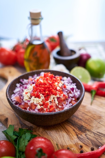 Fazendo molho de molho de salsa tomates de alho picados e cebola em uma tigela de madeira