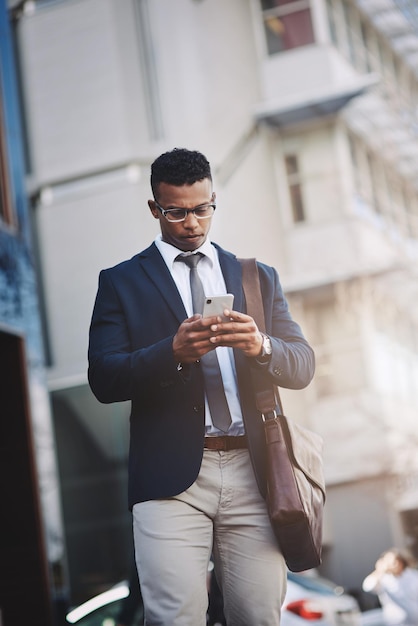 Fazendo negócios se movem diretamente de seu dispositivo Foto de um jovem empresário bonito usando um celular na cidade