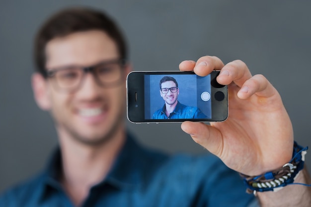 Fazendo selfie feliz. jovem sorridente fazendo selfie com seu telefone inteligente