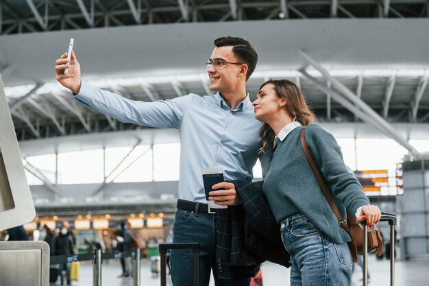 Foto fazendo selfie jovem casal está no aeroporto juntos