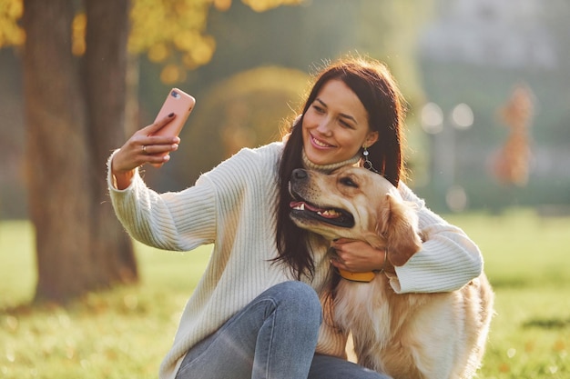 Fazendo selfie Jovem mulher passear com Golden Retriever no parque