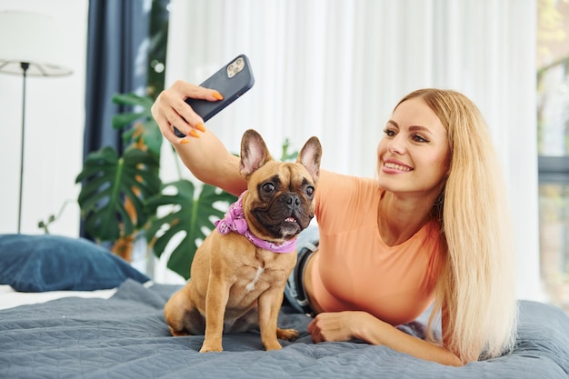 Fazendo selfie Mulher com cachorro pug está em casa durante o dia