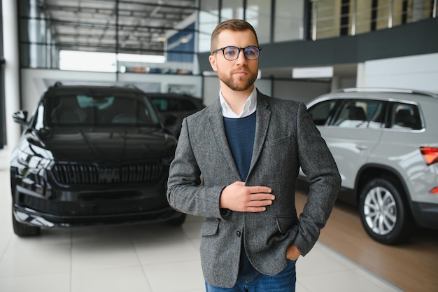 Fazendo sua escolha Retrato horizontal de um jovem de terno olhando para o carro e pensando se deveria comprá-lo