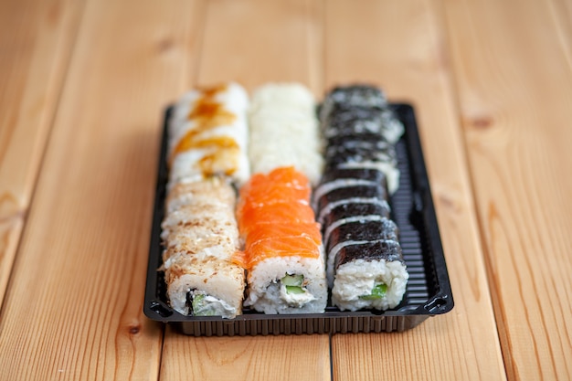 Fazendo sushi e pãezinhos em casa. Sushi com frutos do mar, salada e arroz branco. Comida para família e amigos. Um conjunto de diferentes rolos e sushi em uma bandeja.