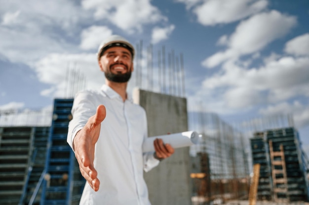 Foto fazendo um acordo estendendo a mão o homem de uniforme está trabalhando no canteiro de obras