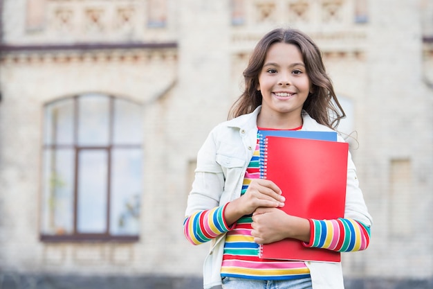 Fazendo um curso extra para um aprendizado mais profundo Educação escolar Curso de escolha Educação moderna Garota sorridente estudante da escola segura livros didáticos para estudar Educação para crianças superdotadas