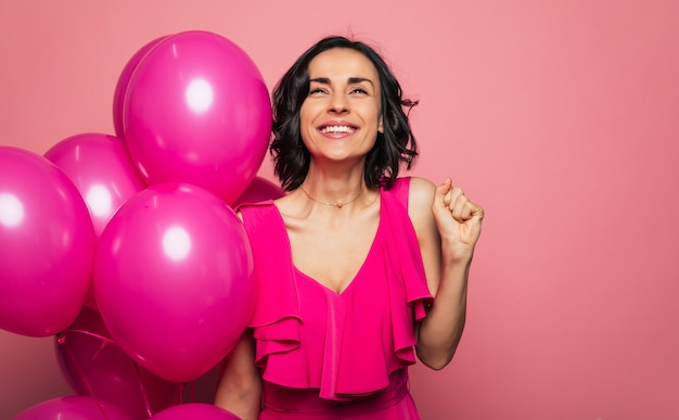 Foto fazendo um pedido. foto de close-up de uma menina morena feliz em uma roupa brilhante, que está olhando para cima com um grande sorriso, segurando balões na mão direita.