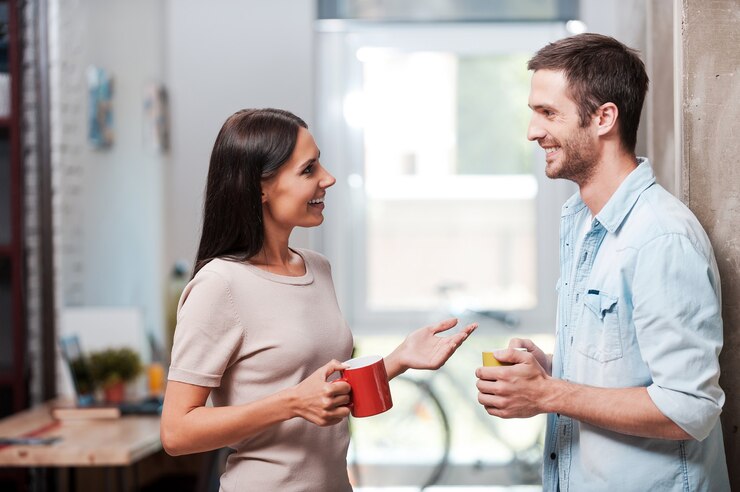 Fazendo uma boa pausa para o café. Dois jovens alegres segurando xícaras de café e conversando enquanto estão no escritório