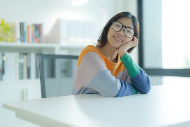 Fazendo uma pausa de estudar na biblioteca é uma jovem sorridente ou estudante usando óculos