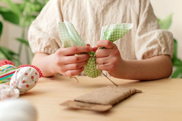 Fazer decorações de Páscoa em close-up de mãos de meninas fazendo ovos de Páscua têxteis em forma de coelho