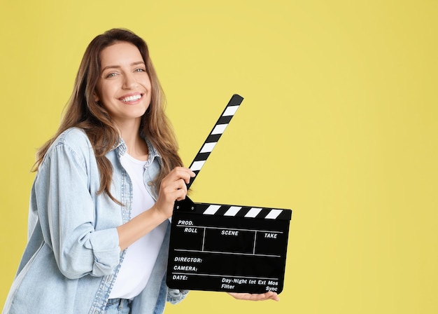 Fazer filme Mulher sorridente com clapperboard em fundo amarelo Espaço para texto