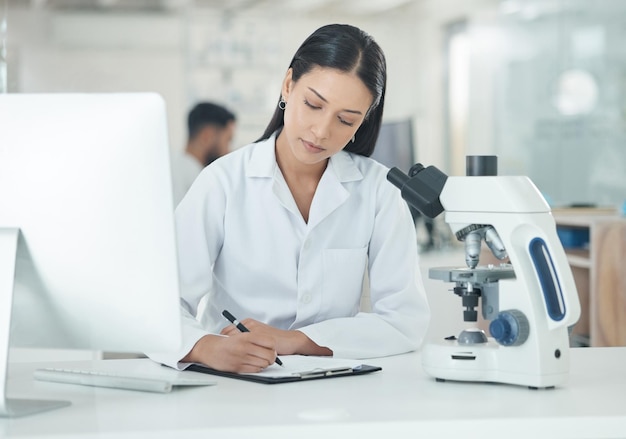 Fazer observações e interpretar descobertas. foto de um jovem cientista escrevendo notas enquanto trabalhava em um laboratório.