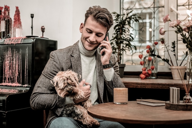 Fazer uma chamada. um homem segurando um cachorro enquanto faz uma ligação