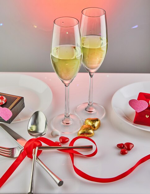Fecha de San Valentín con corazones de caramelo, copas de champán y mesa elegante