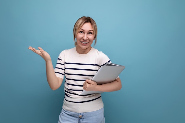 Fechamento de uma loira bem-sucedida freelancer em um suéter listrado segurando um laptop nas mãos