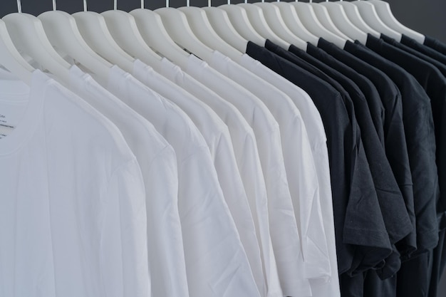 Fechar a coleção de camisetas pretas e brancas penduradas no cabide de madeira