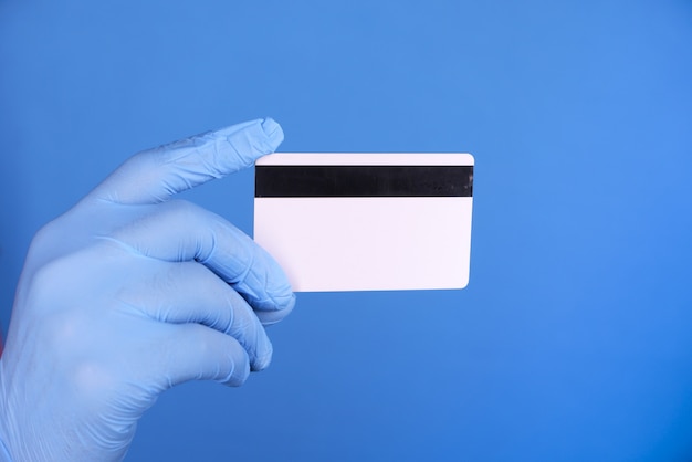 Foto fechar a mão da pessoa com luvas de proteção segurando um cartão de crédito