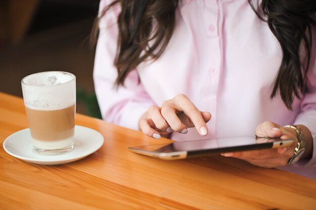 Fechar a mão de uma mulher usando tablet na cafeteria