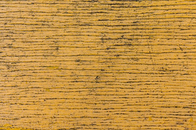 Fechar a textura amarela de madeira rachada da placa pintada vintage
