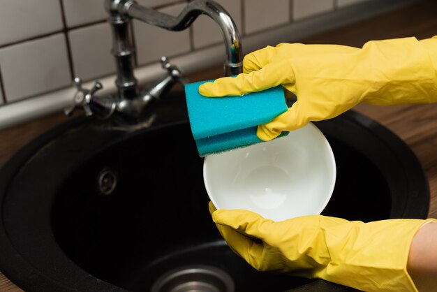 Fechar as mãos da mulher lavando pratos na cozinha