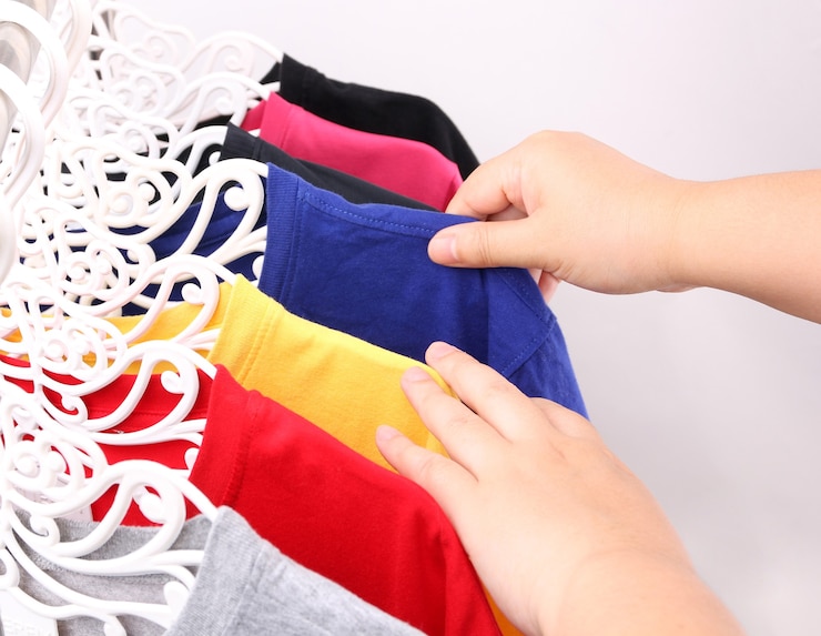 Foto fechar coleção de t-shirts coloridas penduradas.