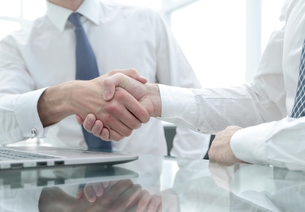 Fechar colegas apertando as mãos sobre uma mesa