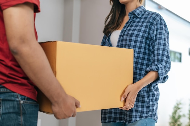 Fechar Foco seletivo Jovens casais asiáticos ajudam a segurar uma caixa de papelão pesada a entrar em nova casa com felicidade nova casa em movimento